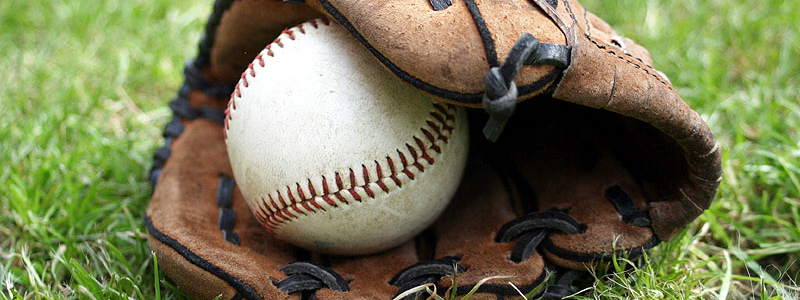 A ball in a glove laying in the grass.